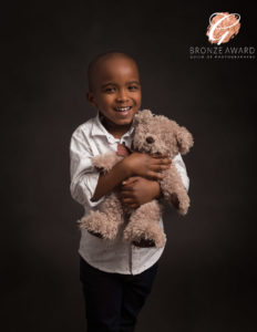 boy holding teddy bear smiling in a photoshoot by Family and Child Photographer in Basingstoke, Hampshire