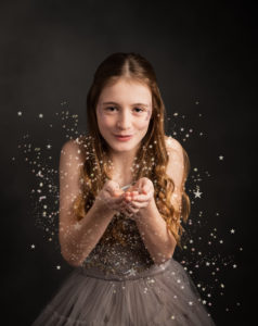 Girl with long hair blowing glitter to the camera by family photographer in basingstoke hampshire